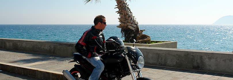 Ein Mann mit einem Motorrad neben dem Meer in Ligurien