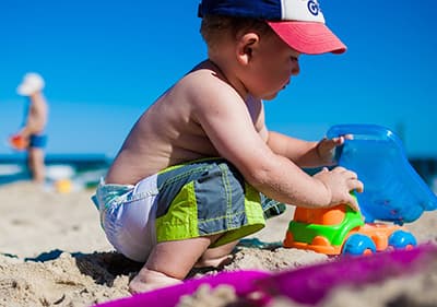 Ein Kleinkind spielt am Sandstrand
